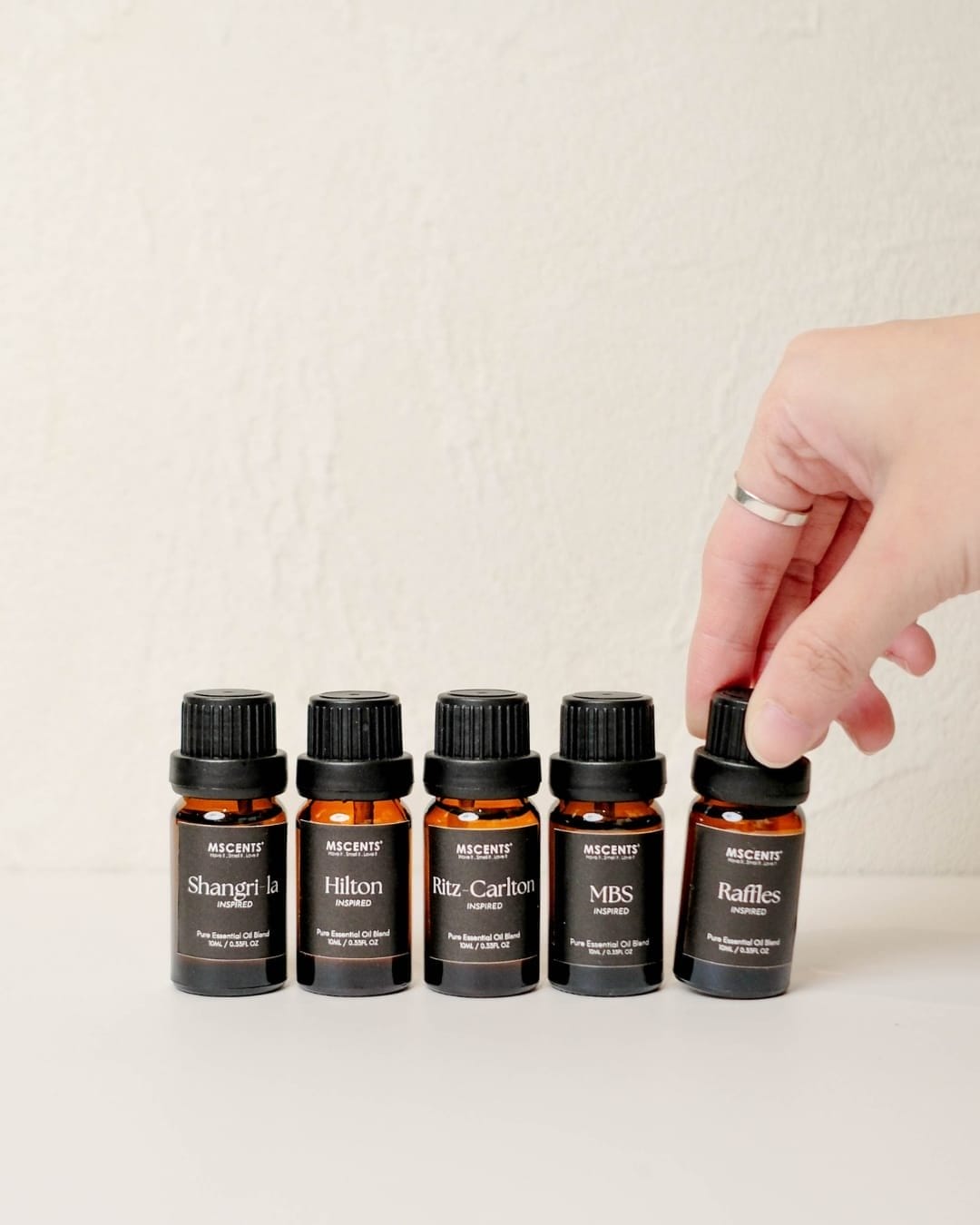 A hand reaching out to get a small essential oil bottle