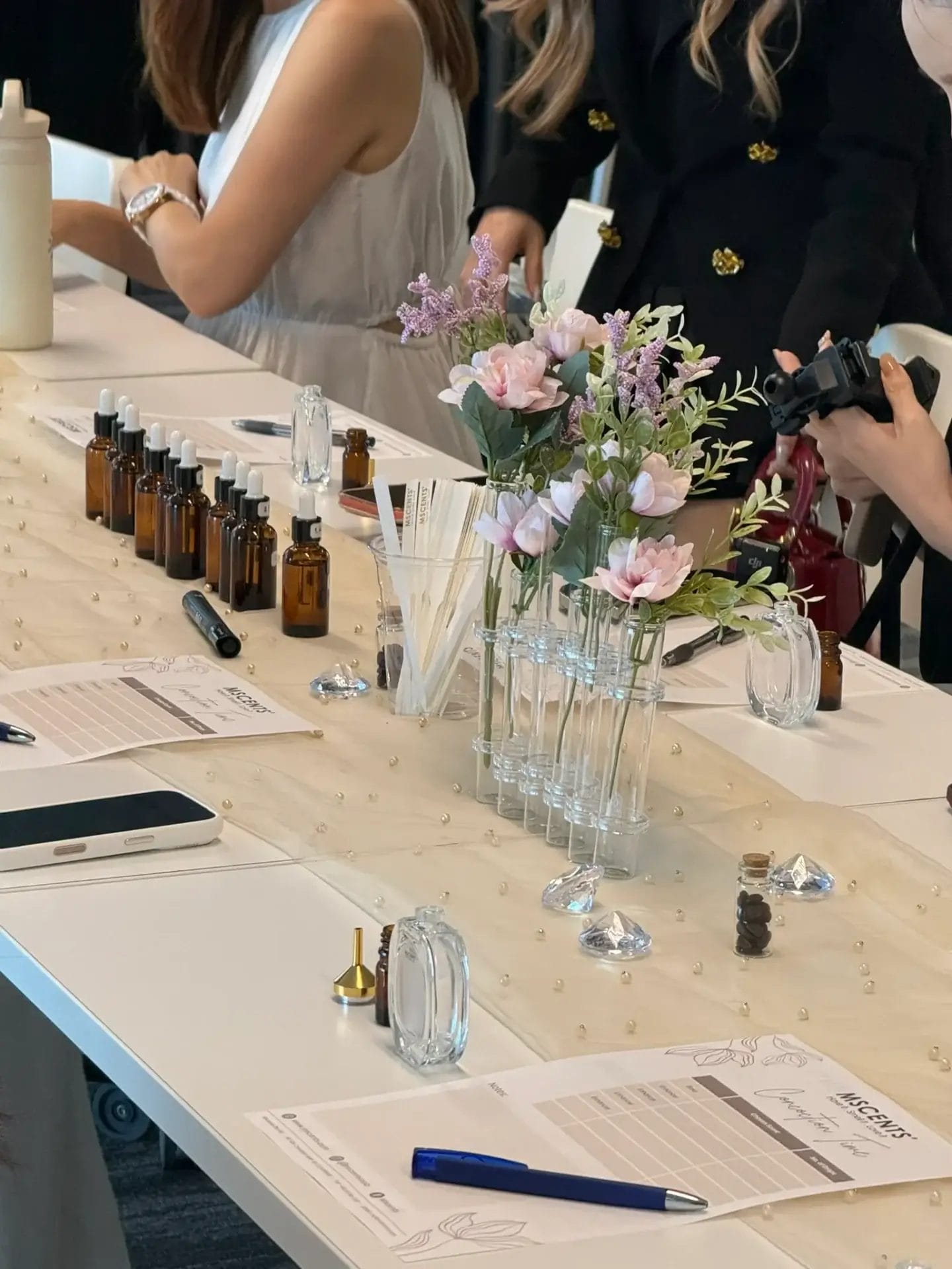 Women sitting at a long table during perfume-making class